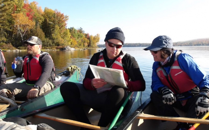 People sit in canoes floating close together and examine a map.